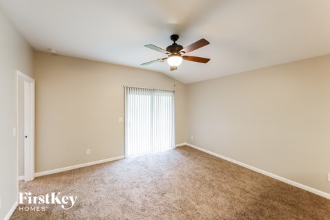 a spacious living room with carpet and a ceiling fan