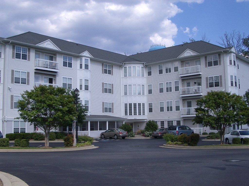 a large white apartment building with cars parked in front