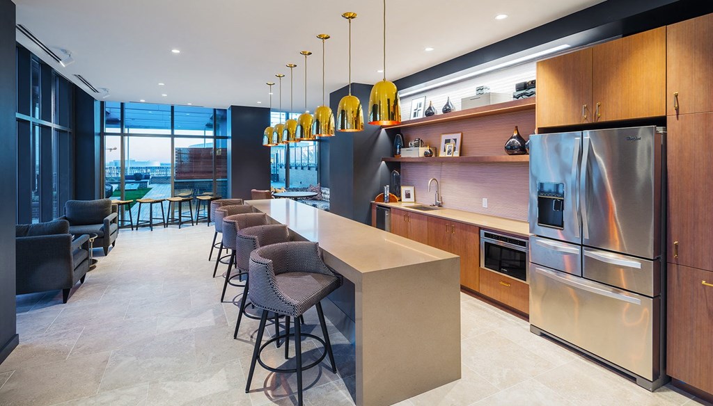 a kitchen with a long island with chairs and a stainless steel refrigerator