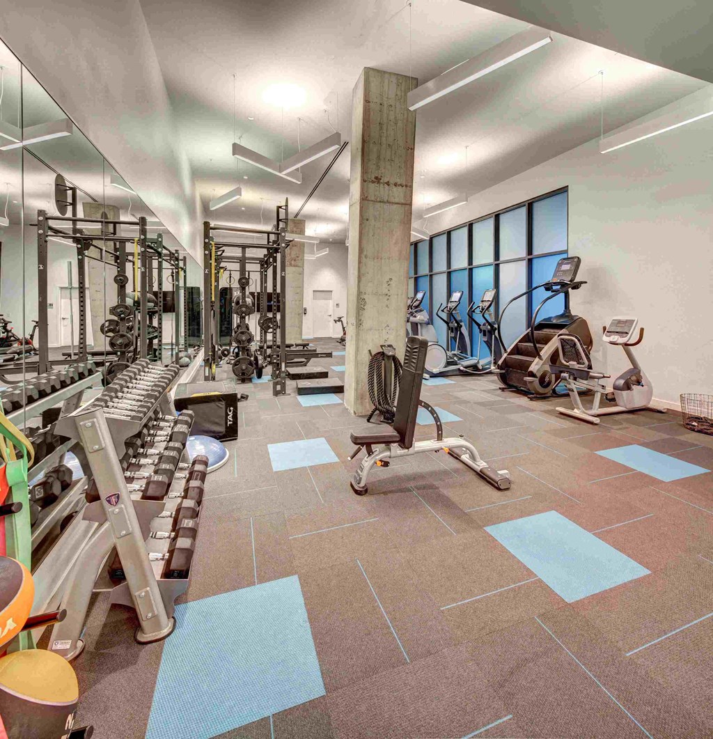 a gym with weights and cardio equipment in a building with windows