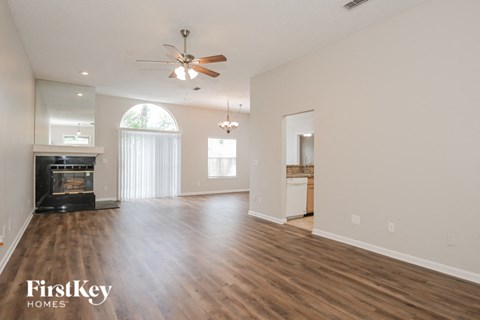 an empty living room with a fireplace and a ceiling fan