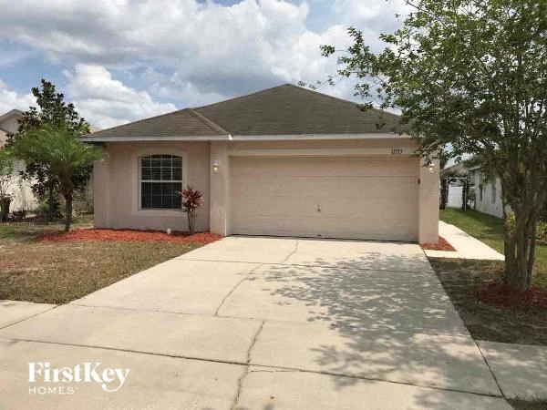 A house with a garage and a tree in front of it.