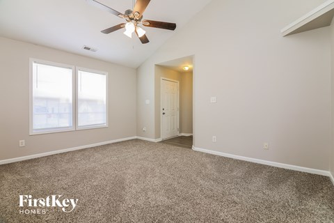 a spacious living room with carpet and a ceiling fan