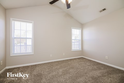 a bedroom with carpet and two windows and a ceiling fan