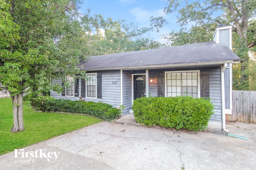 a small blue house with a porch and a driveway