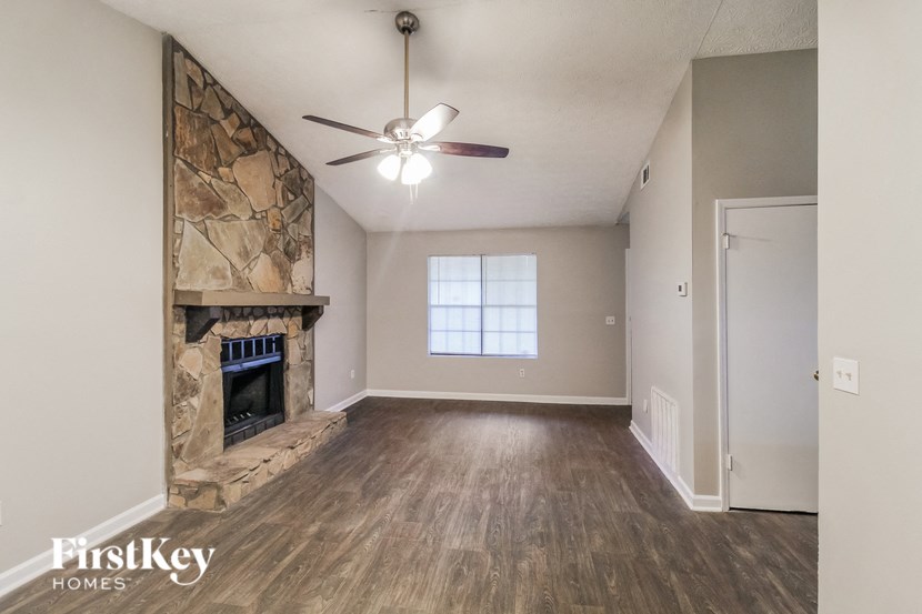 an empty living room with a fireplace and a ceiling fan