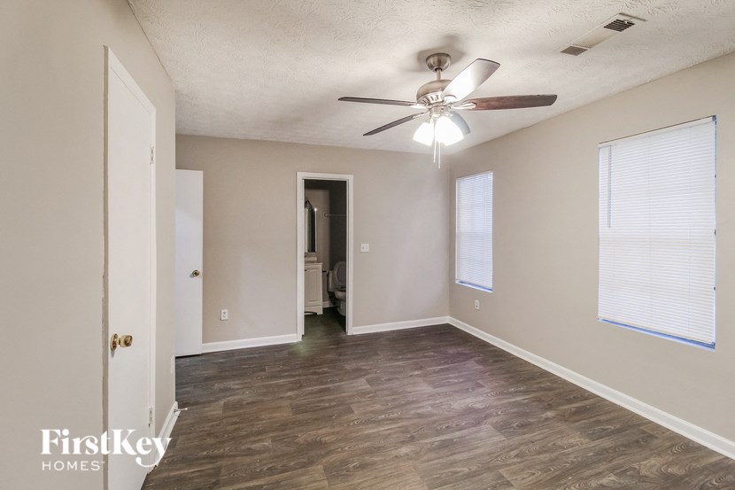 an empty living room with a ceiling fan and a door to a bathroom