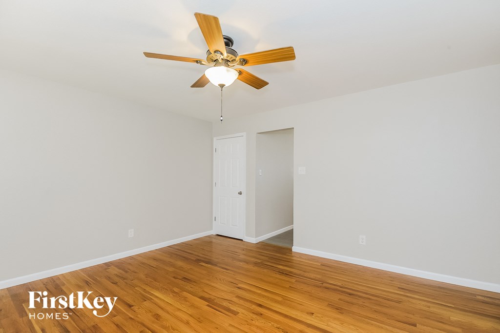 A room with a ceiling fan and wooden floors.