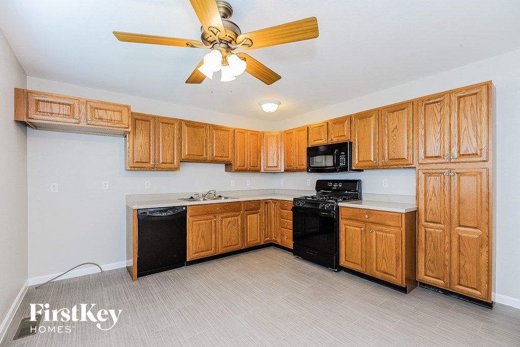 A kitchen with wooden cabinets and a black dishwasher.