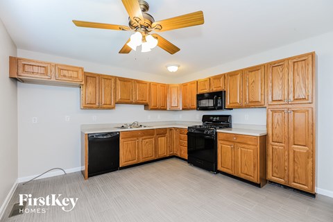 A kitchen with wooden cabinets and a black dishwasher.