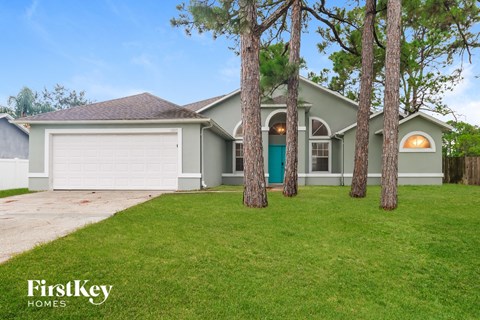 A house with a green lawn and trees in front of it.