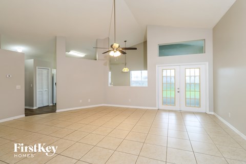 A spacious room with a ceiling fan and a large window.