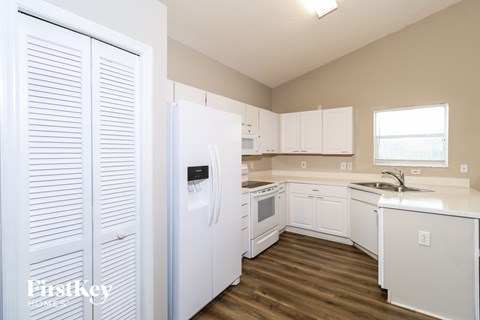 A kitchen with white appliances and cabinets.