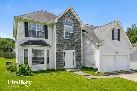 a white house with a stone facade and white garage doors