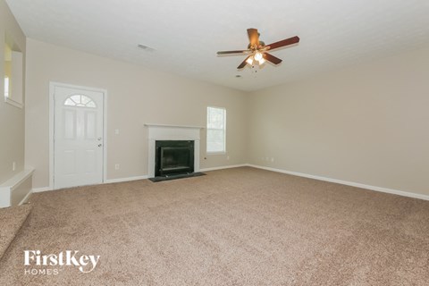 an empty living room with a fireplace and a ceiling fan