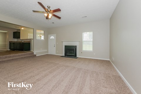 an empty living room with a fireplace and a ceiling fan