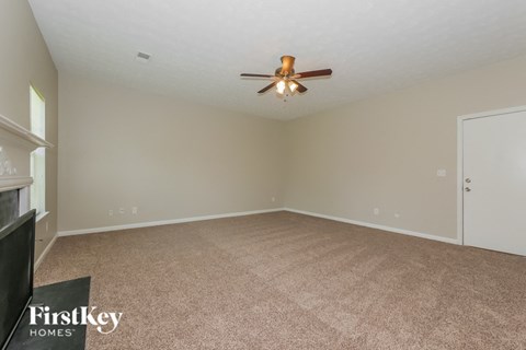 an empty living room with a ceiling fan and carpet