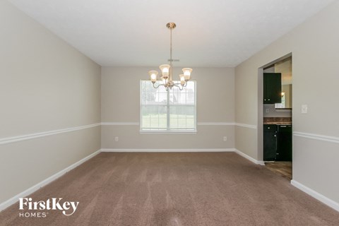 an empty living room with carpet and a chandelier