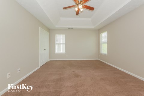 a living room with a carpet and a ceiling fan