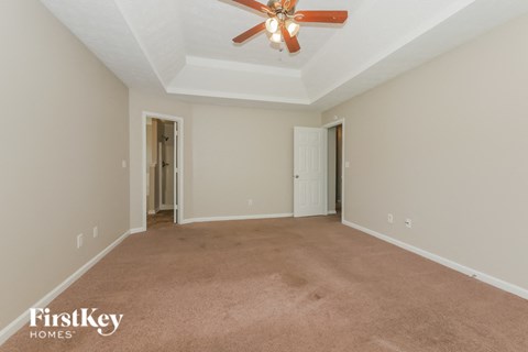 a spacious living room with carpet and a ceiling fan