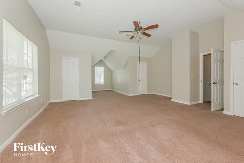 an empty living room with a ceiling fan and white walls