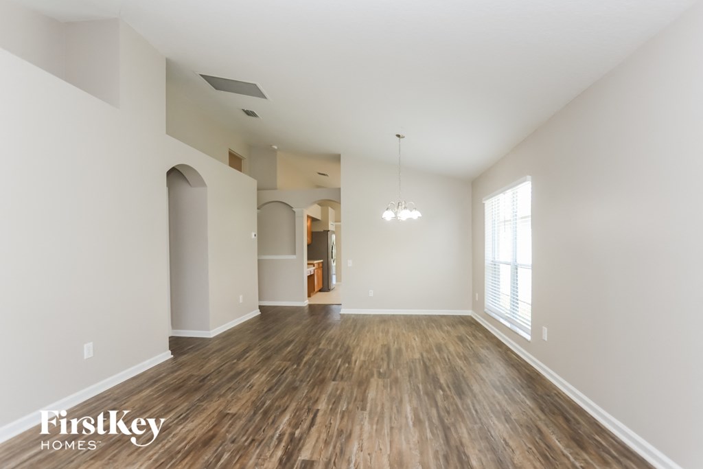 an empty living room with wood flooring and a large window