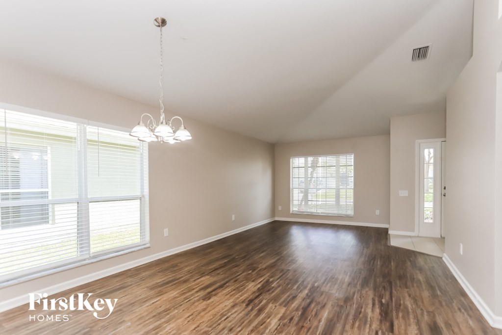 the living room of an empty house with wood flooring and large windows