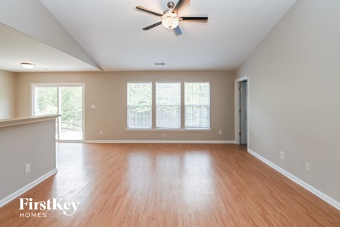 an empty living room with wood floors and a ceiling fan
