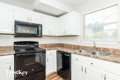 A kitchen with white cabinets and a black stove top oven.