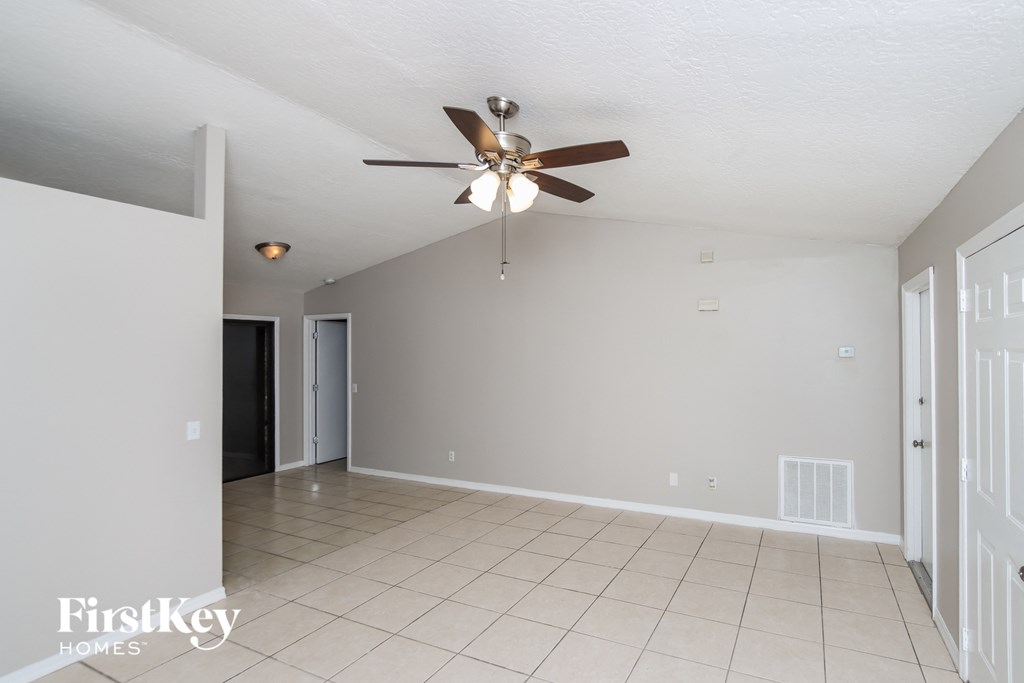 an empty living room with a ceiling fan and a tiled floor