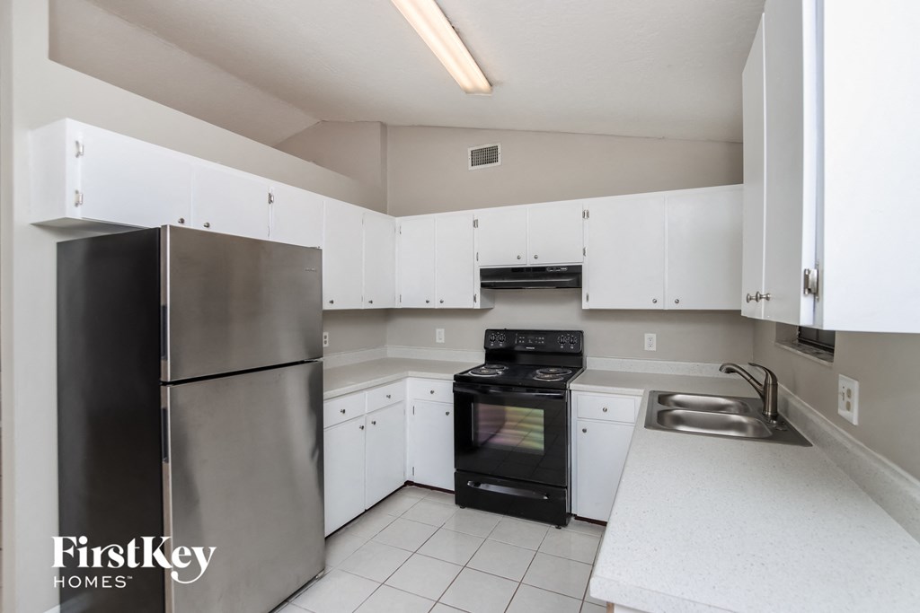 a kitchen with white cabinets and a black stove and refrigerator