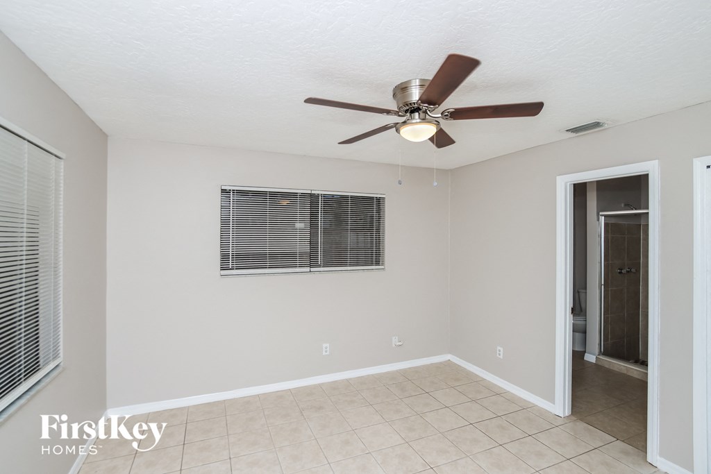 a living room with a ceiling fan and a door to a bathroom