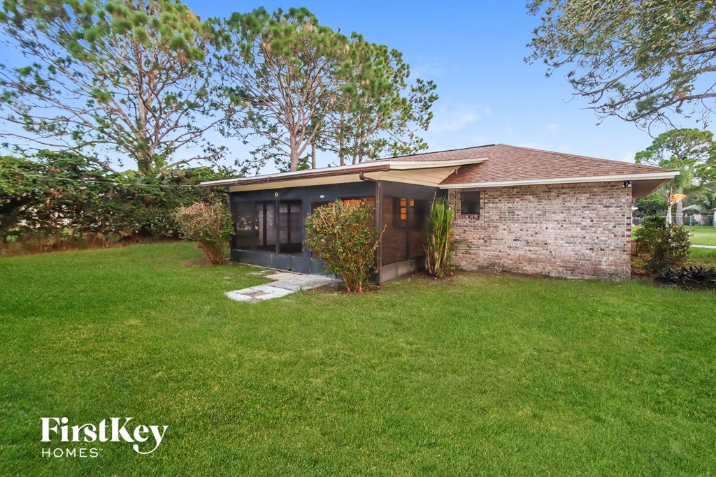 a small brick house with a grassy yard and a tree