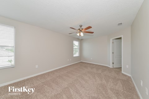 a spacious living room with carpet and a ceiling fan