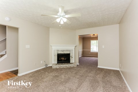 A living room with a fireplace and a ceiling fan.