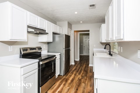 A kitchen with white cabinets and a wooden floor.