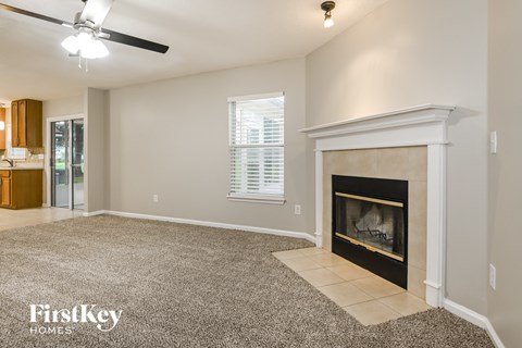 A living room with a fireplace and a ceiling fan.