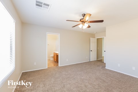 a spacious living room with a ceiling fan and a carpet