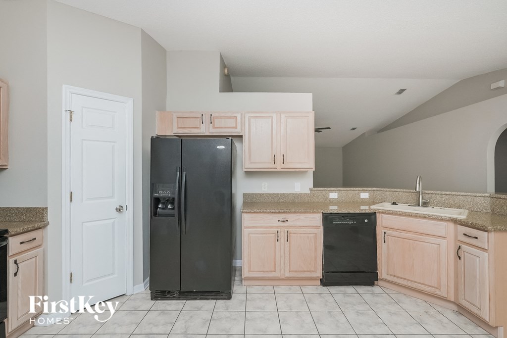 a kitchen with white cabinets and a black refrigerator