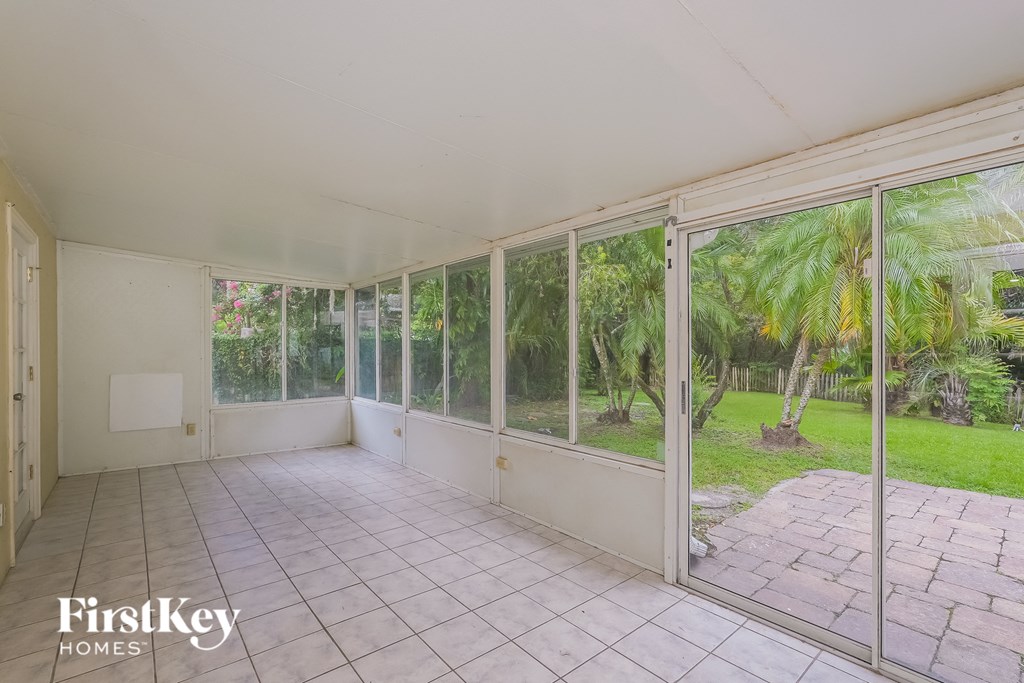 an empty living room with large windows and a tiled floor