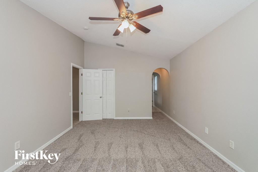 a spacious living room with carpet and a ceiling fan