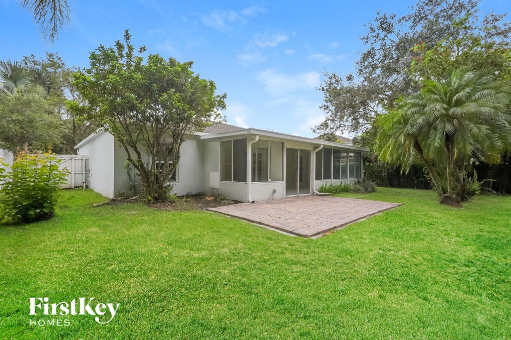 a white house with a yard and palm trees