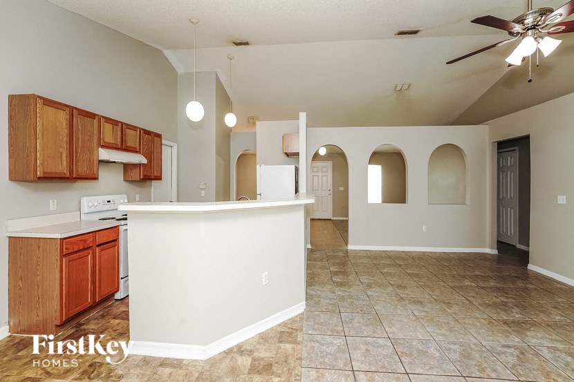 an open kitchen and living room with an island and a ceiling fan