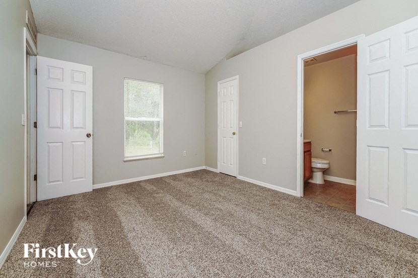 a bedroom with a carpeted floor and a door to a bathroom