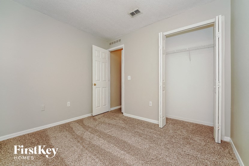 a bedroom with a door to a closet and a carpeted floor