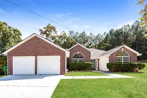 a brick house with a white garage door and a lawn