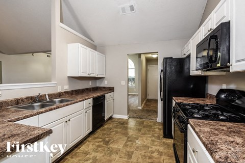 a kitchen with white cabinets and black appliances and granite counter tops