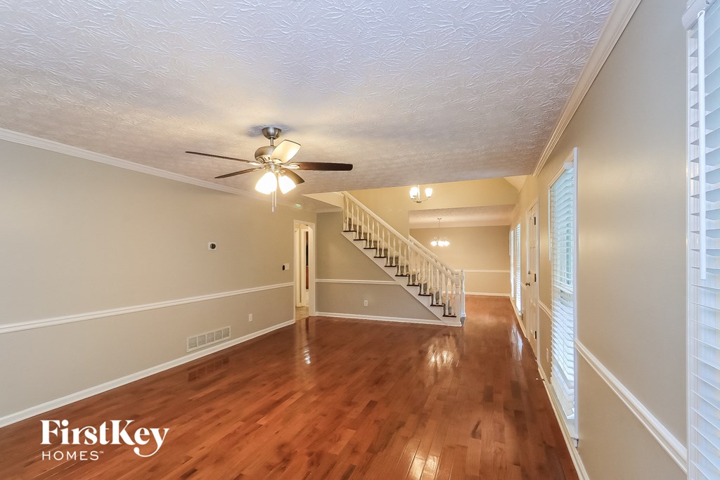 A spacious room with wooden floors and a staircase leading to another level.