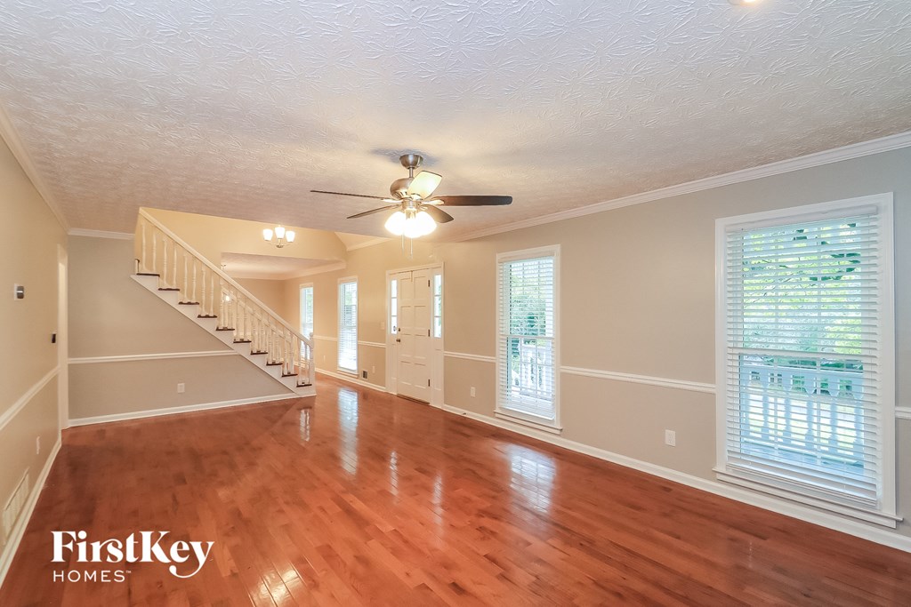 A spacious room with wooden floors and a staircase leading to another level.