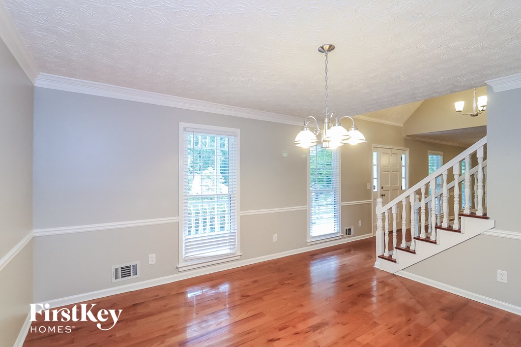 A spacious room with wooden floors and a staircase.